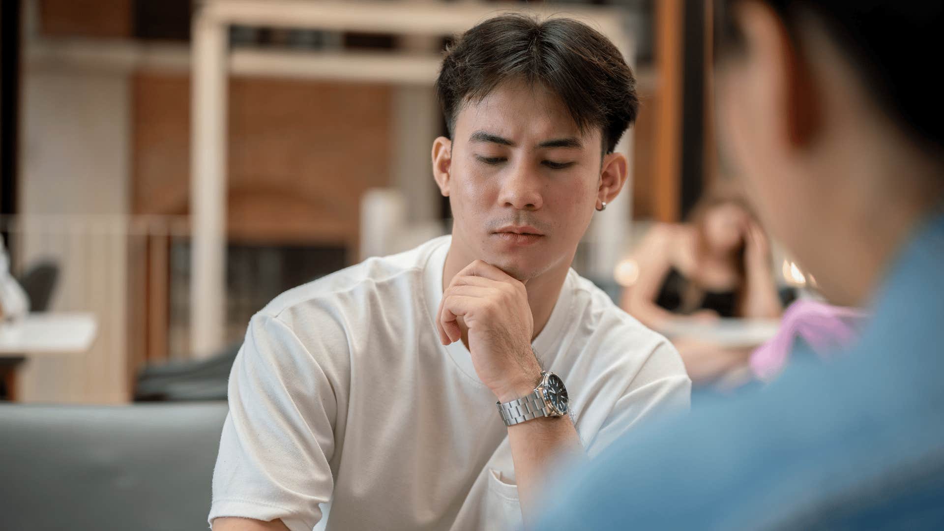 man in white shirt looking down as he says sorry i'm being difficult to friend