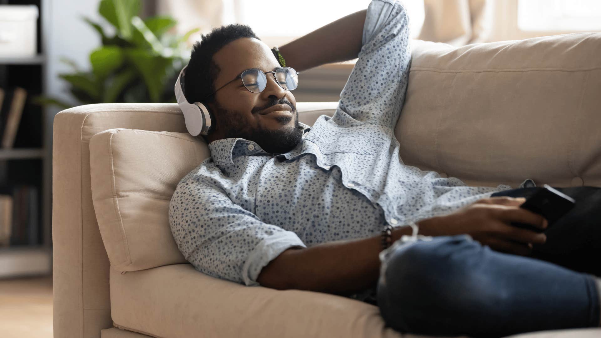 man listening to music on couch as he thinks i like to keep to myself