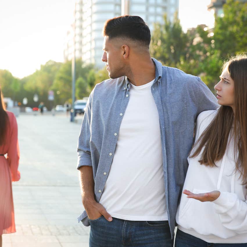 man turned away from his partner looking at another woman