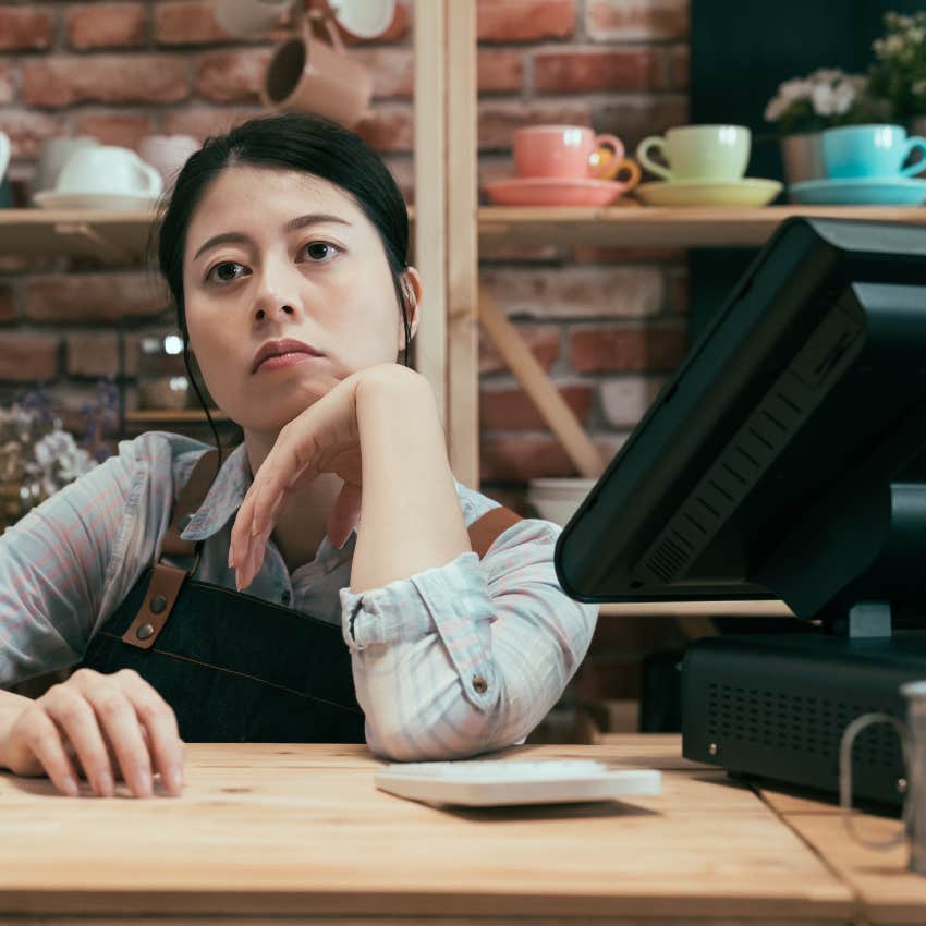 Unhappy fast food worker at the cash register of a restaurant 