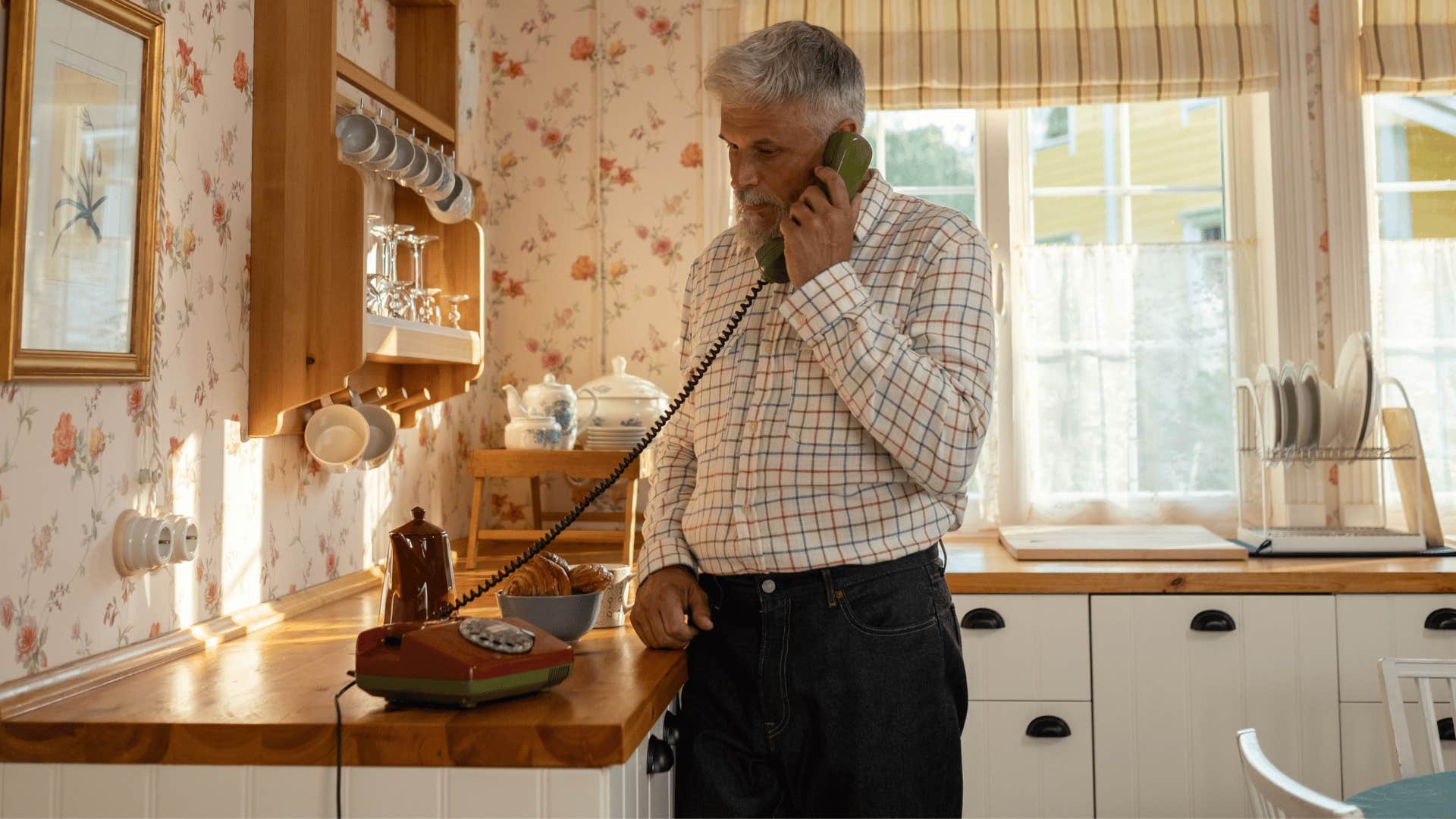 older man calling friends from the kitchen landline