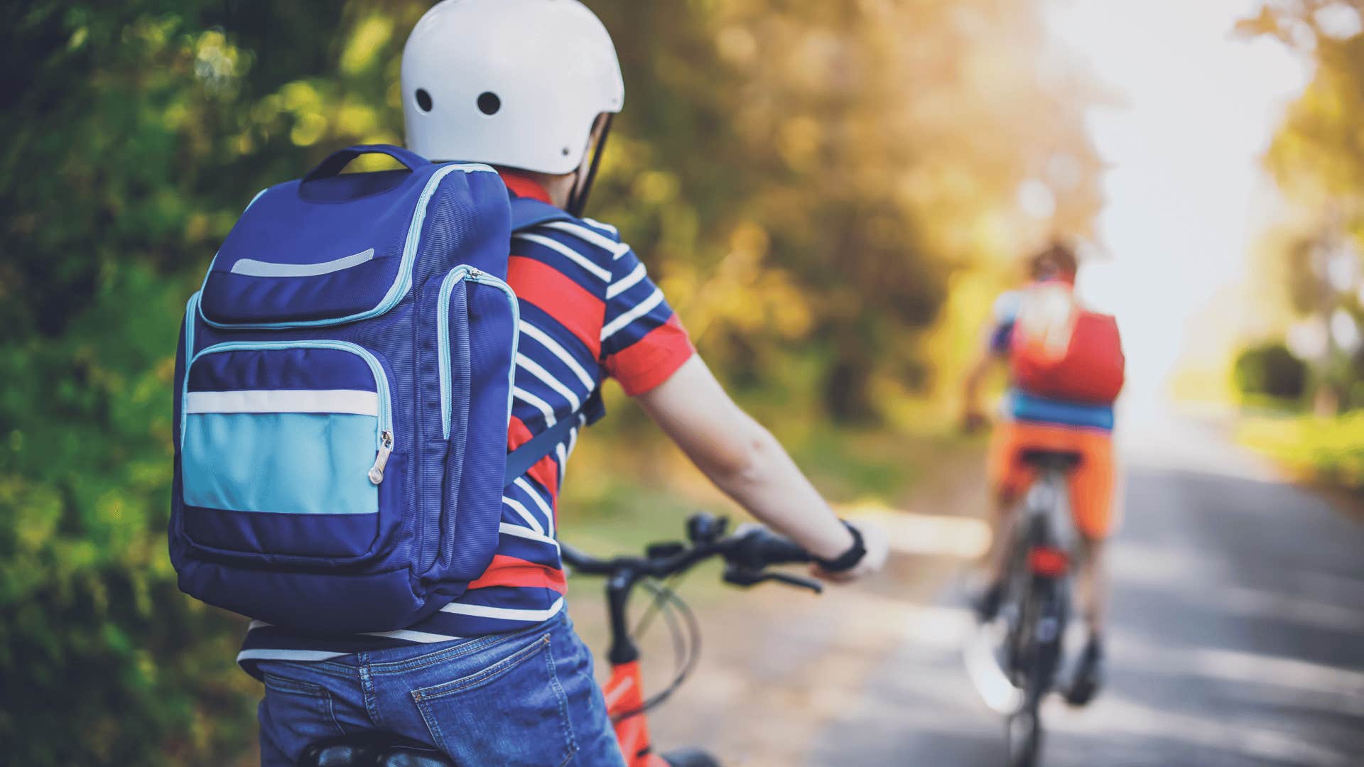 kid in blue backpack riding their bikes freely around the neighborhood