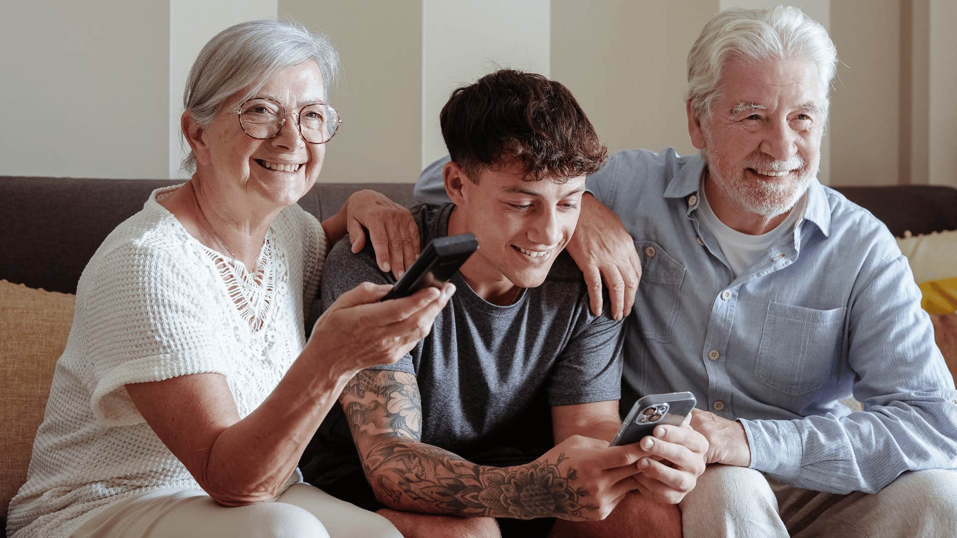 young man with tattoos on phone as he doesn't want to share one screen with the entire family
