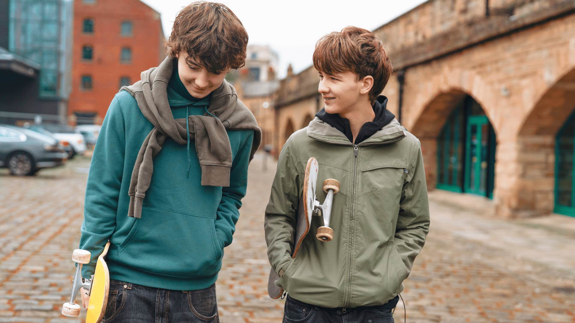 two kids with skateboards walking to school or a friend's house on their own