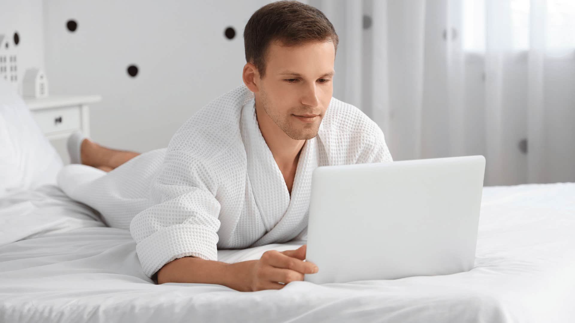 man in white robe looking at his work calendar on computer