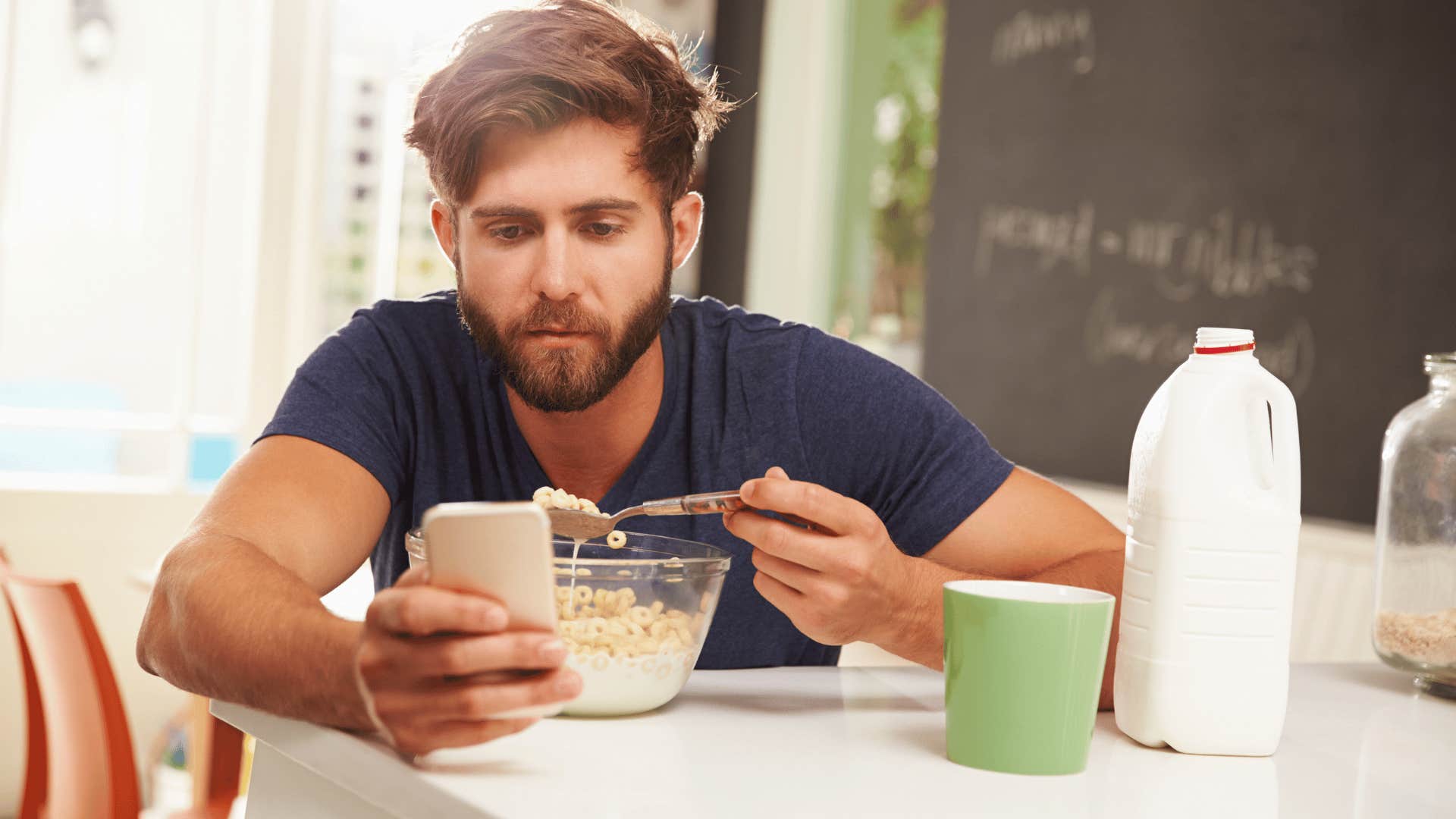 man eating a bowl of cereal in the kitchen