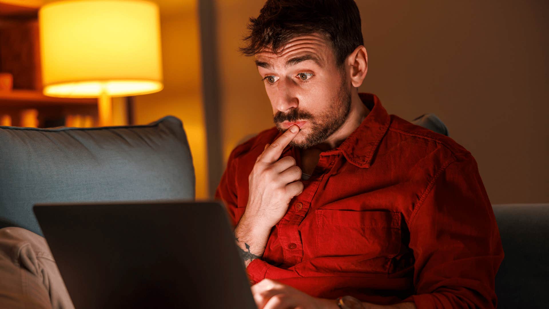 man sitting in quiet dark room working on laptop