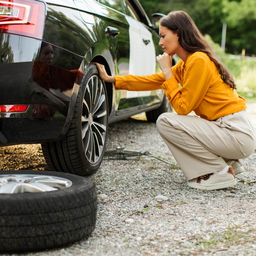 woman who doesn't panic during emergencies replacing flat tire with spare
