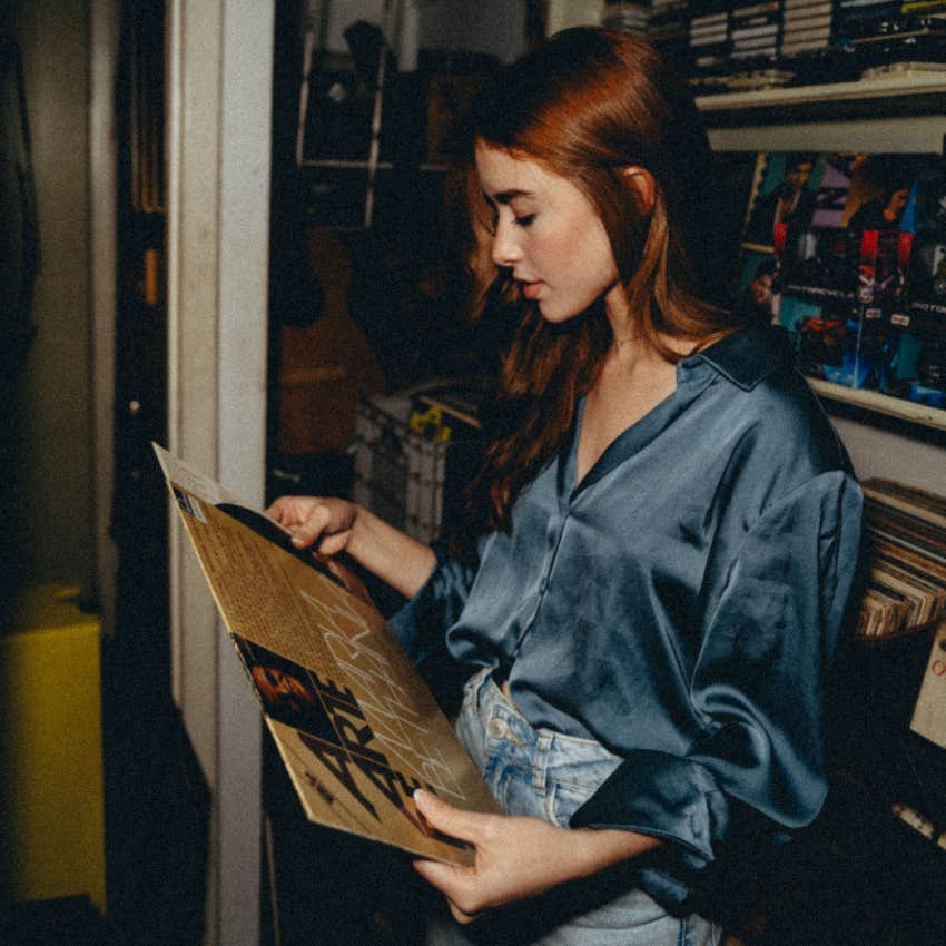 young woman holding vinyl record from her parents' collection