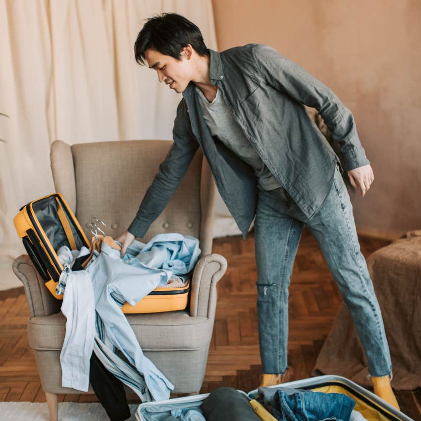 man putting clothes onto a chair in his home