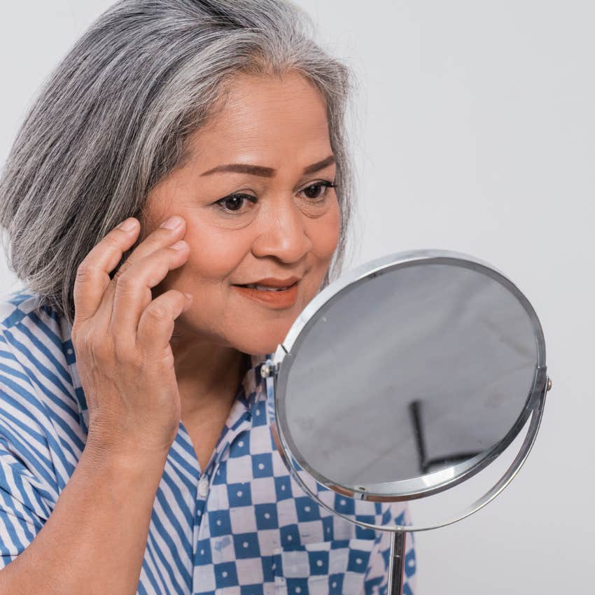 pressured woman looking in the mirror hoping she looks younger