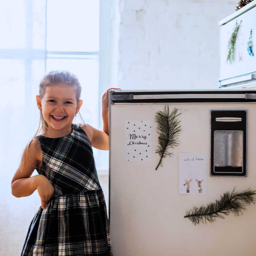 little girl standing in front of an open fridge