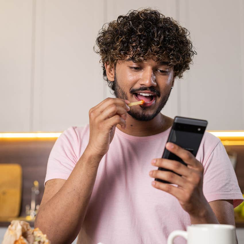 laid-back man happy eating french fries and scrolling the internet