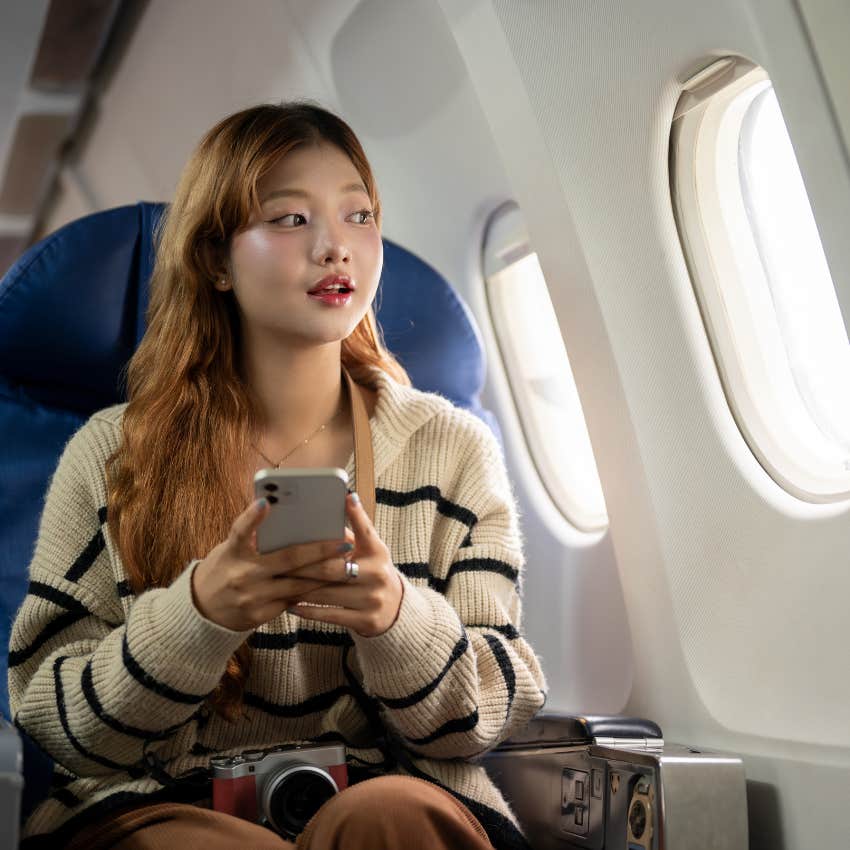 woman who spends money on travel looks happily out airplane window