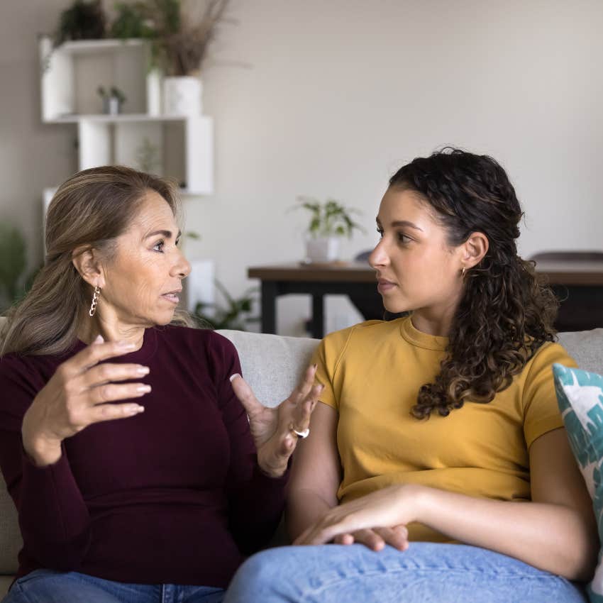 young woman sitting on a couch intently listening to older woman speak 