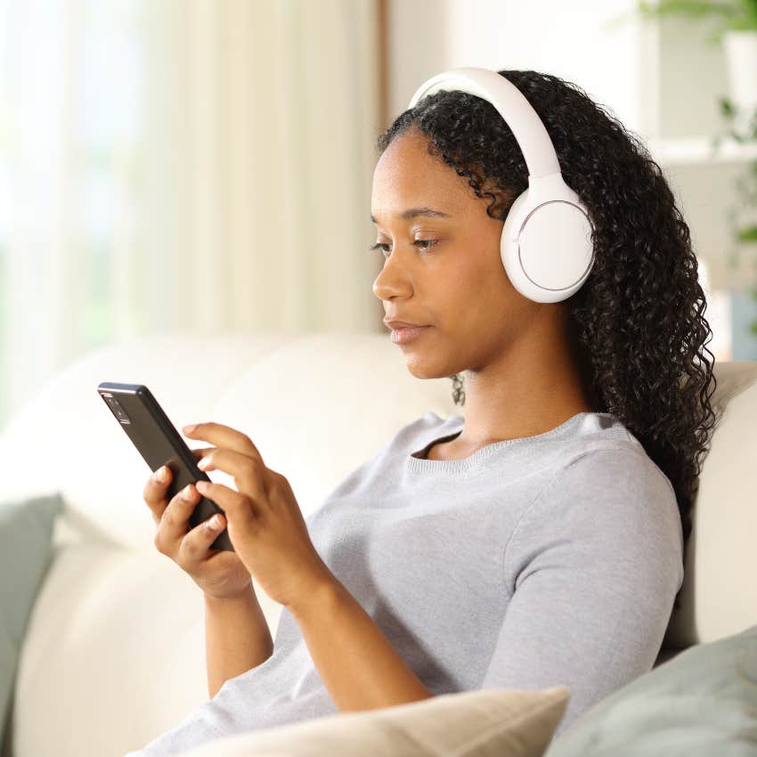 curious woman listening to podcast while sitting on a couch