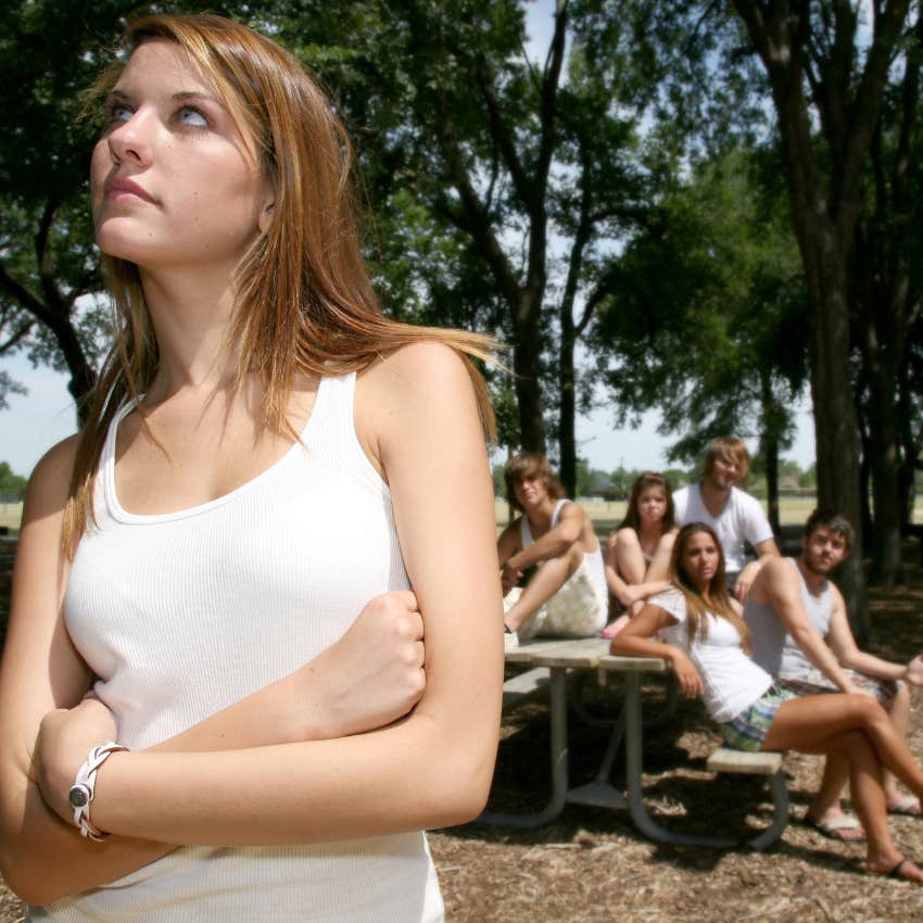 woman physically and mentally detached from her group of friends 