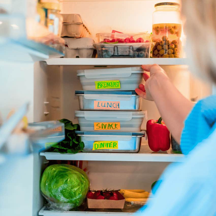 woman placing meal prep containers in fridge