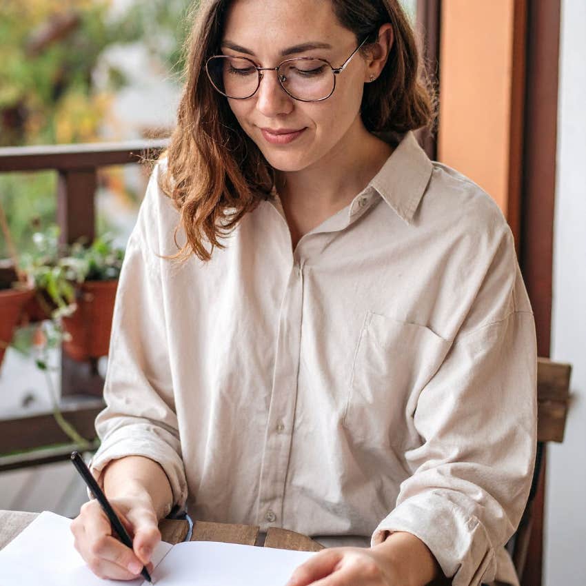 woman writing in her journal doing self-reflection