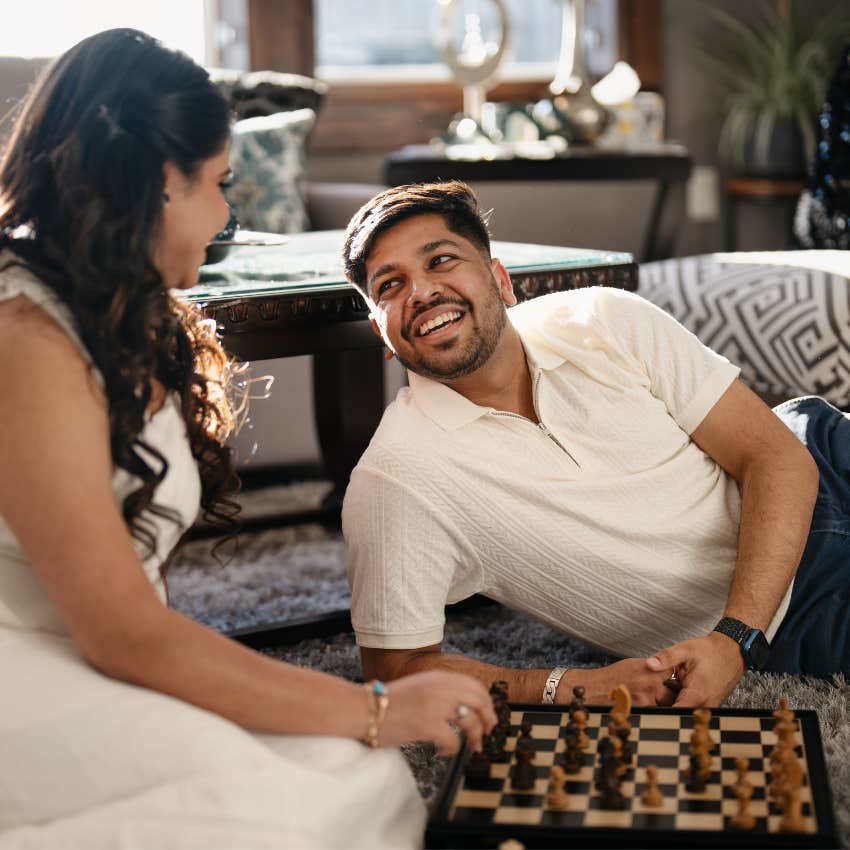 Long-term couple laughing and playing a board game together during a relaxed evening at home