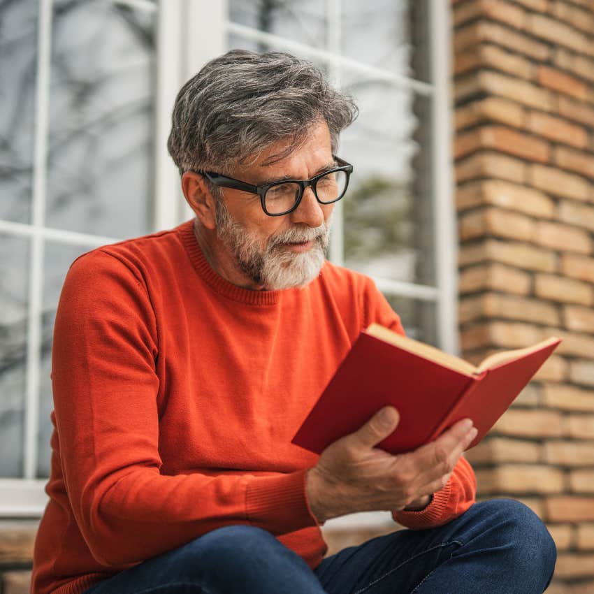 man in glasses who needs a lot of downtime to function reading a book on his porch