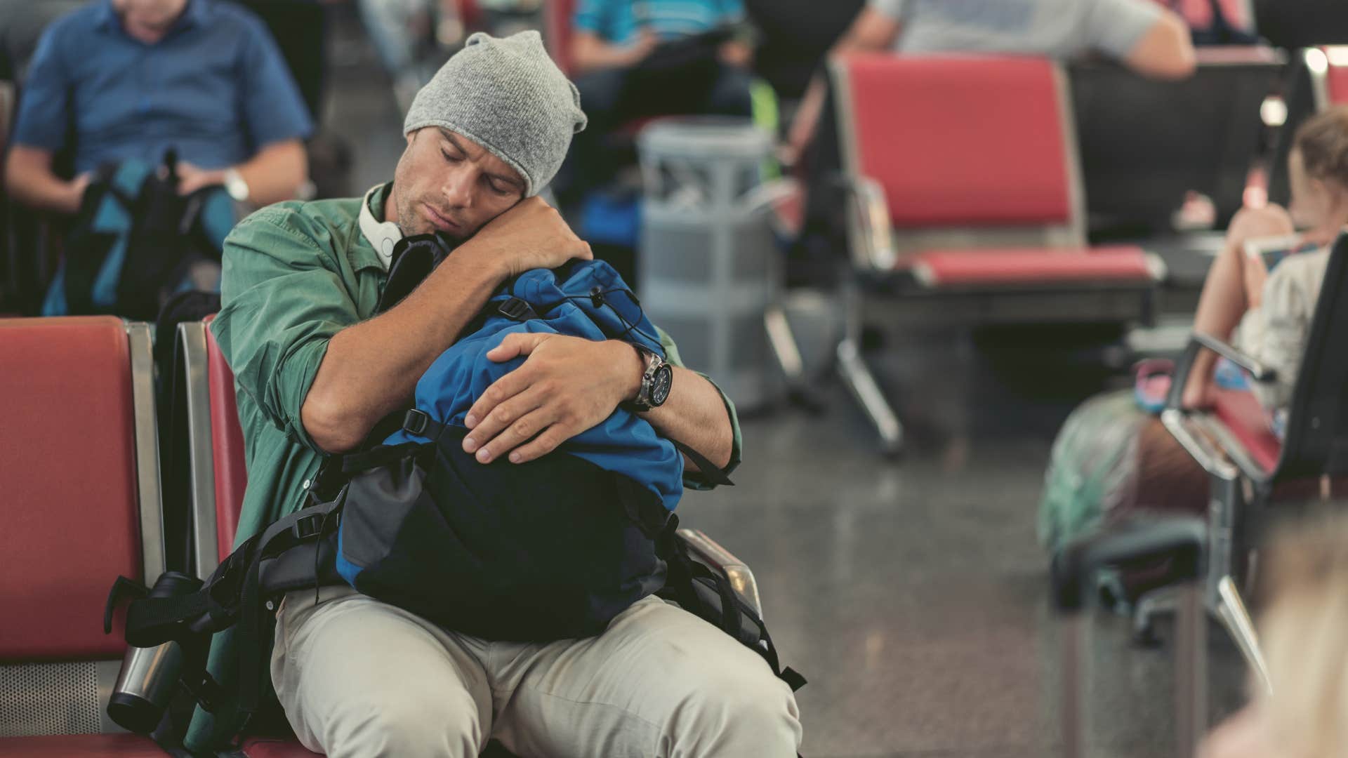 man who needs naps and quiet time to function taking a short nap in an airport waiting for his flight