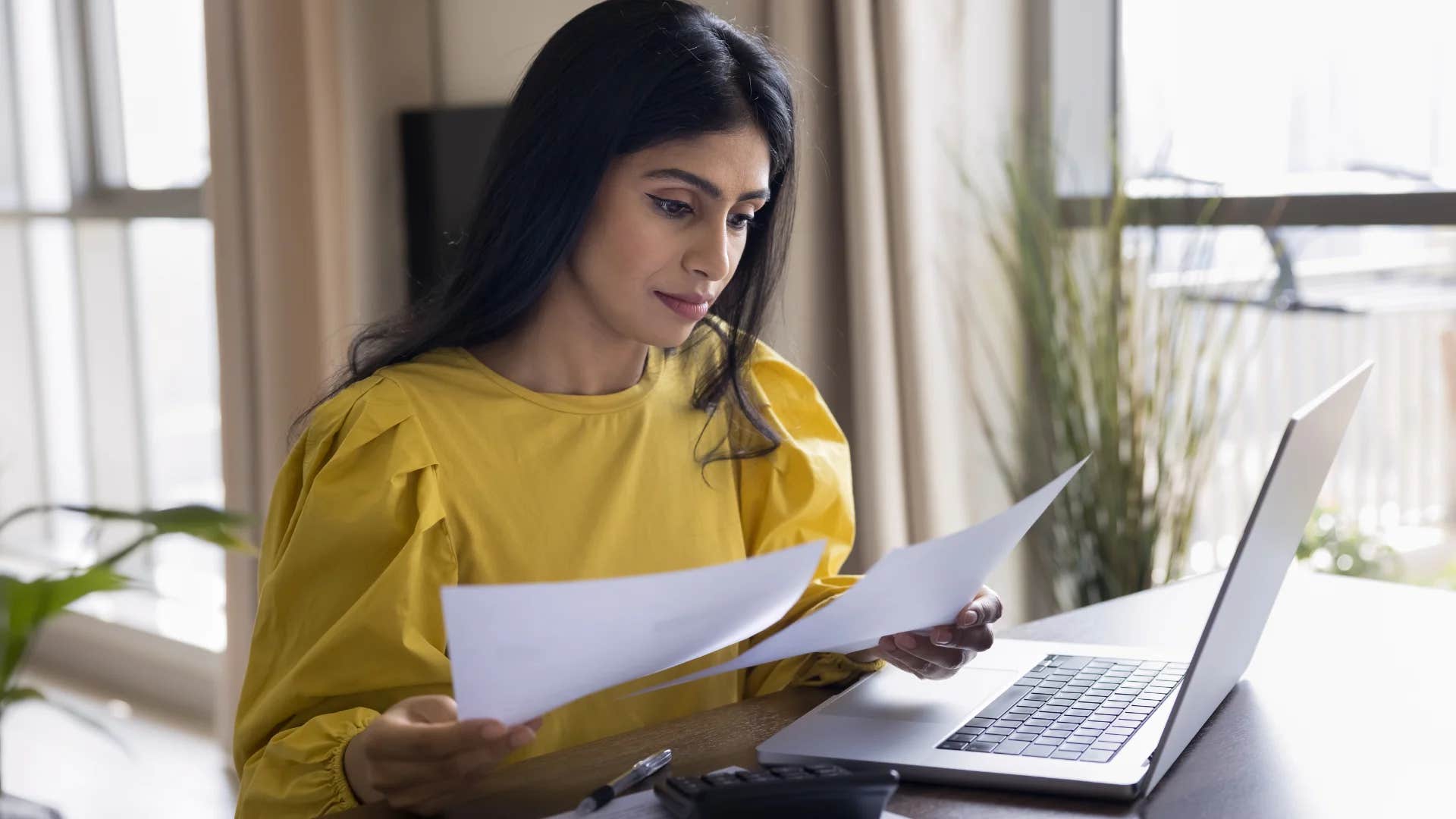 young woman feeling guilty for spending money looking at her bills