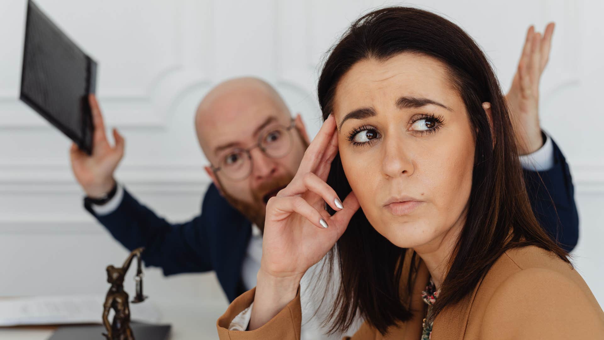 sad young woman having a hard time setting boundaries with yelling colleague