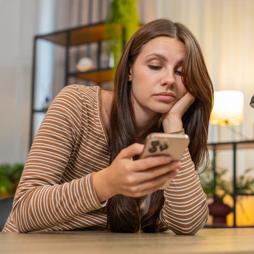 disinterested woman whose parents never played with her as a kid staring at phone 