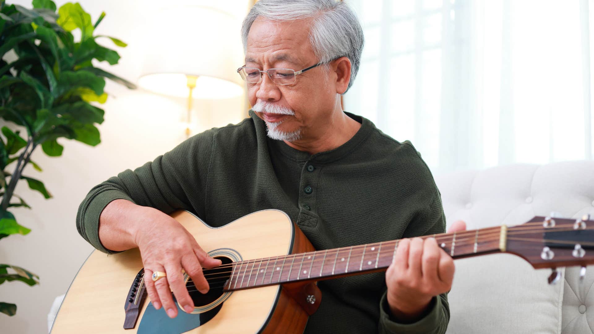 retired introvert man happily playing the guitar