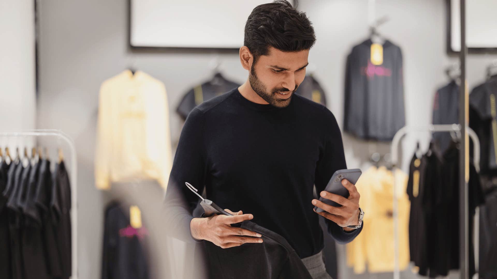 man in black shirt checking prices because he never buys anything new