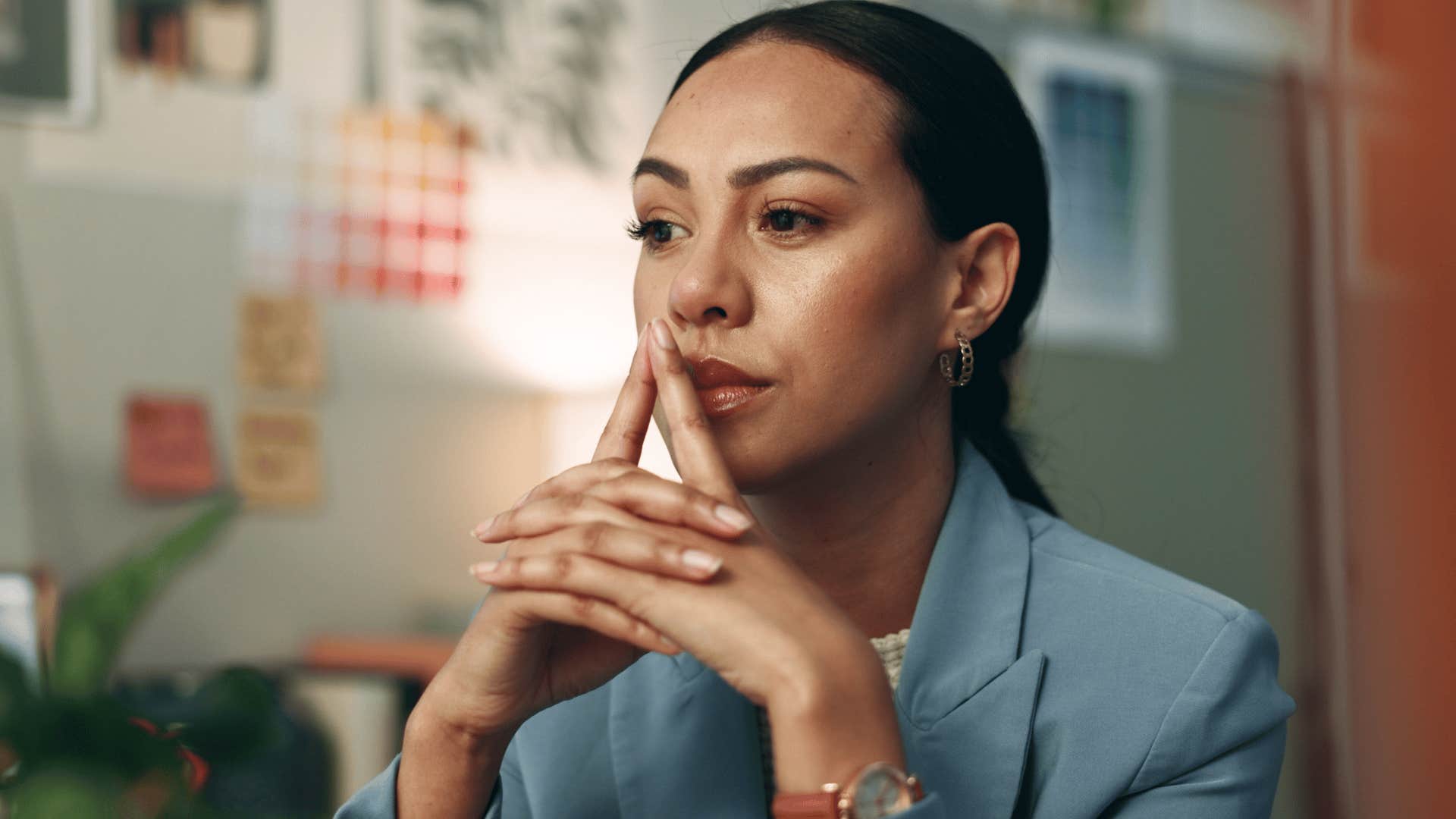 woman in gray jacket overthinks small decisions as she thinks deeply at desk