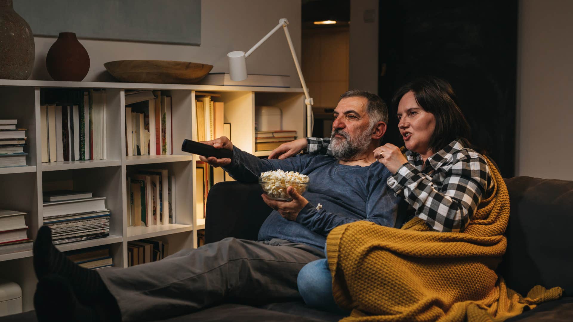 gen x couple who is happy about their early bedtime watching a movie knows being unavailable early at night is beneficial
