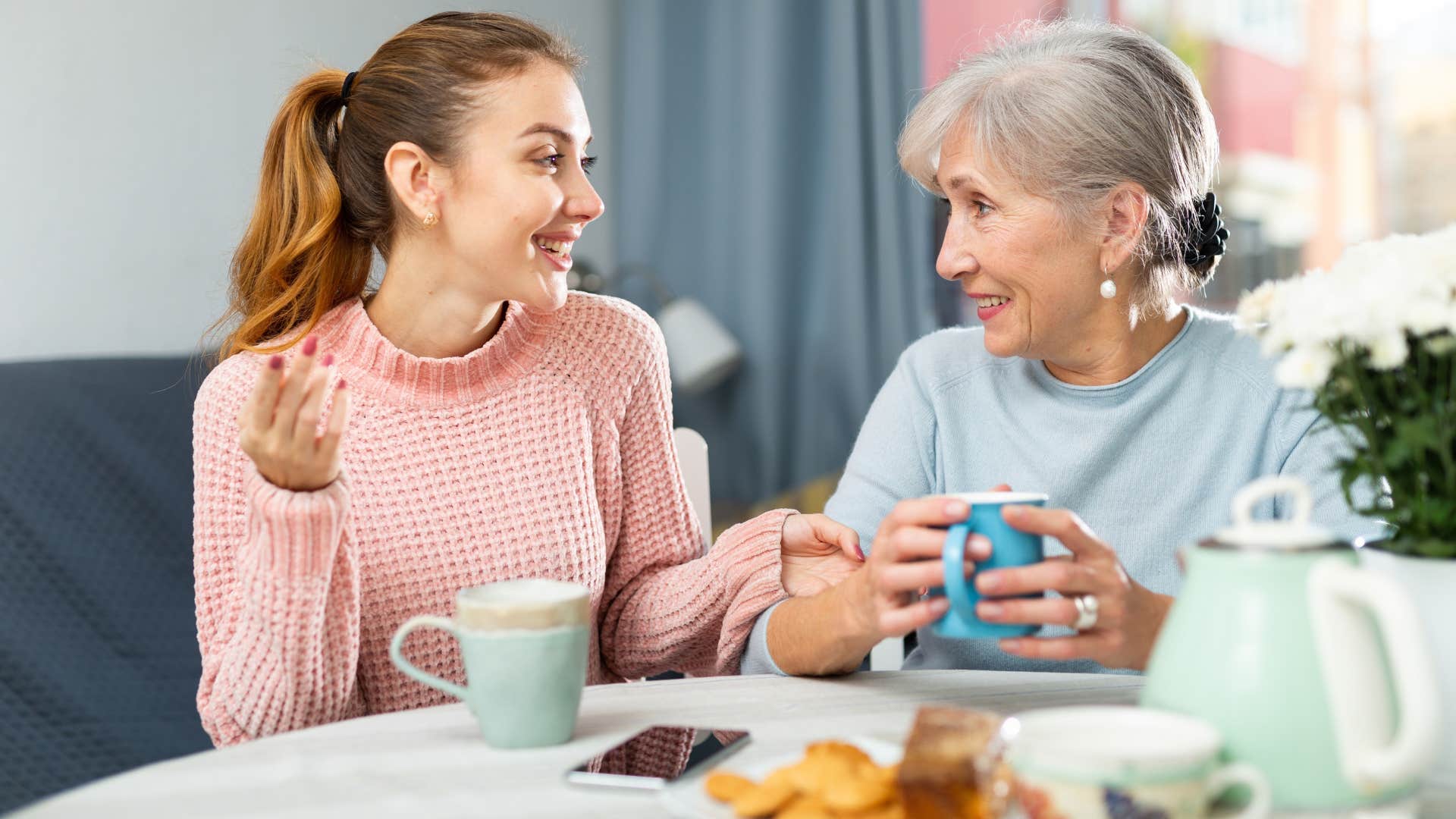 teen granddaughter having heart-to-heart with grandma over tea