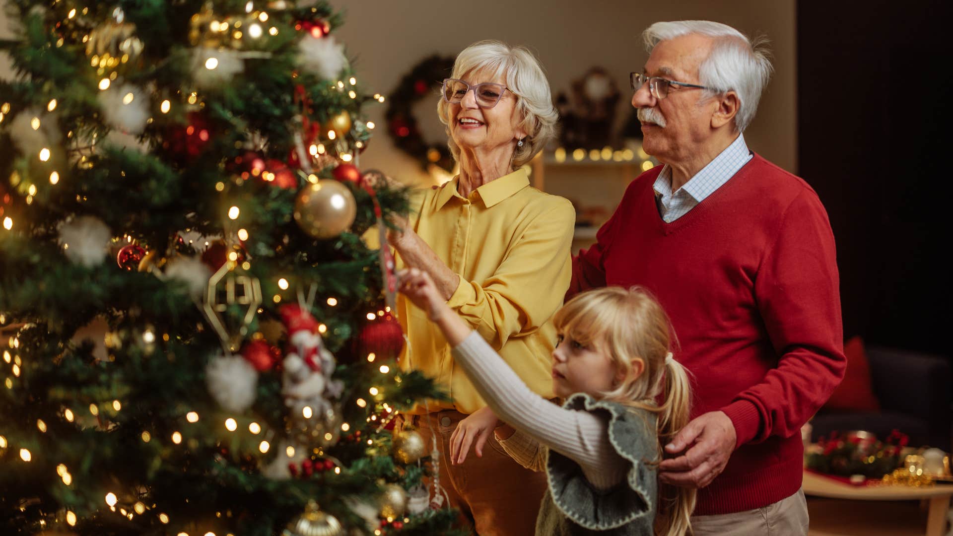 grandparents enjoying the holiday tradition of decorating the tree with granddaughter