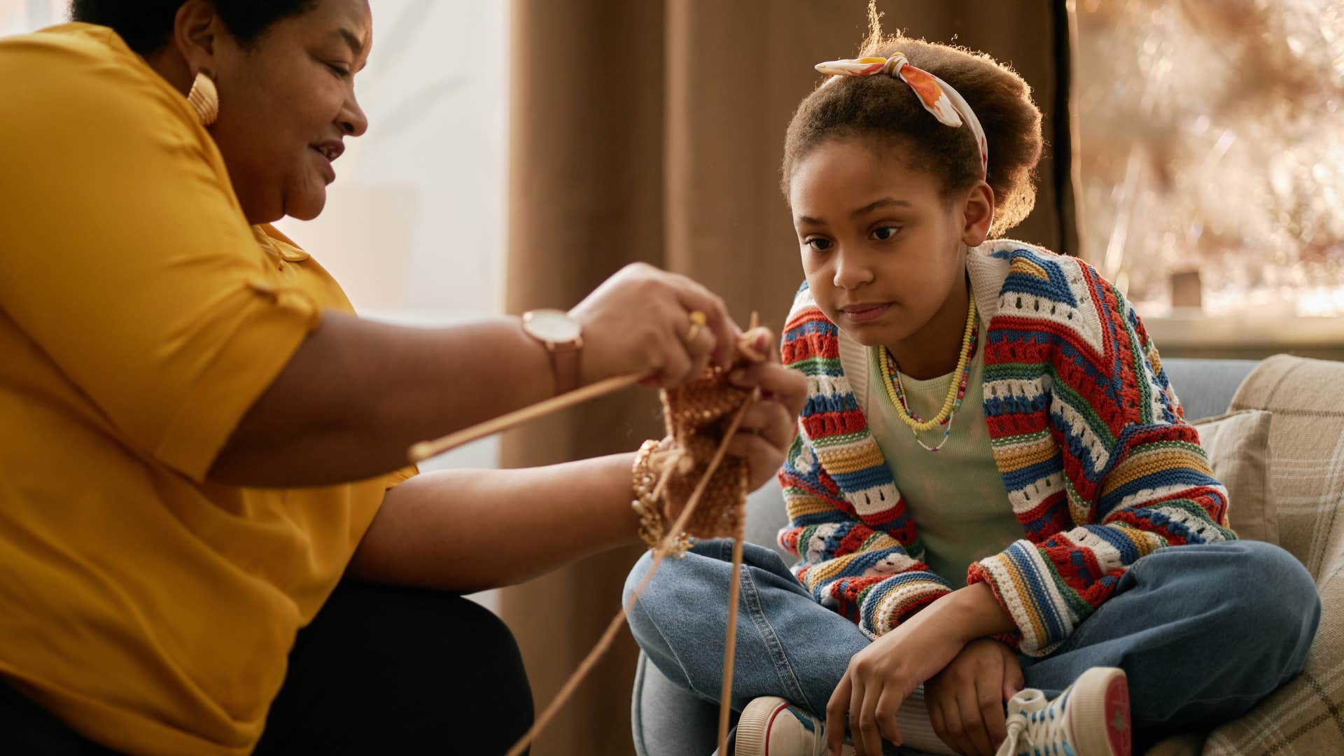 grandma teaching granddaughter how to knit sharing her hobby