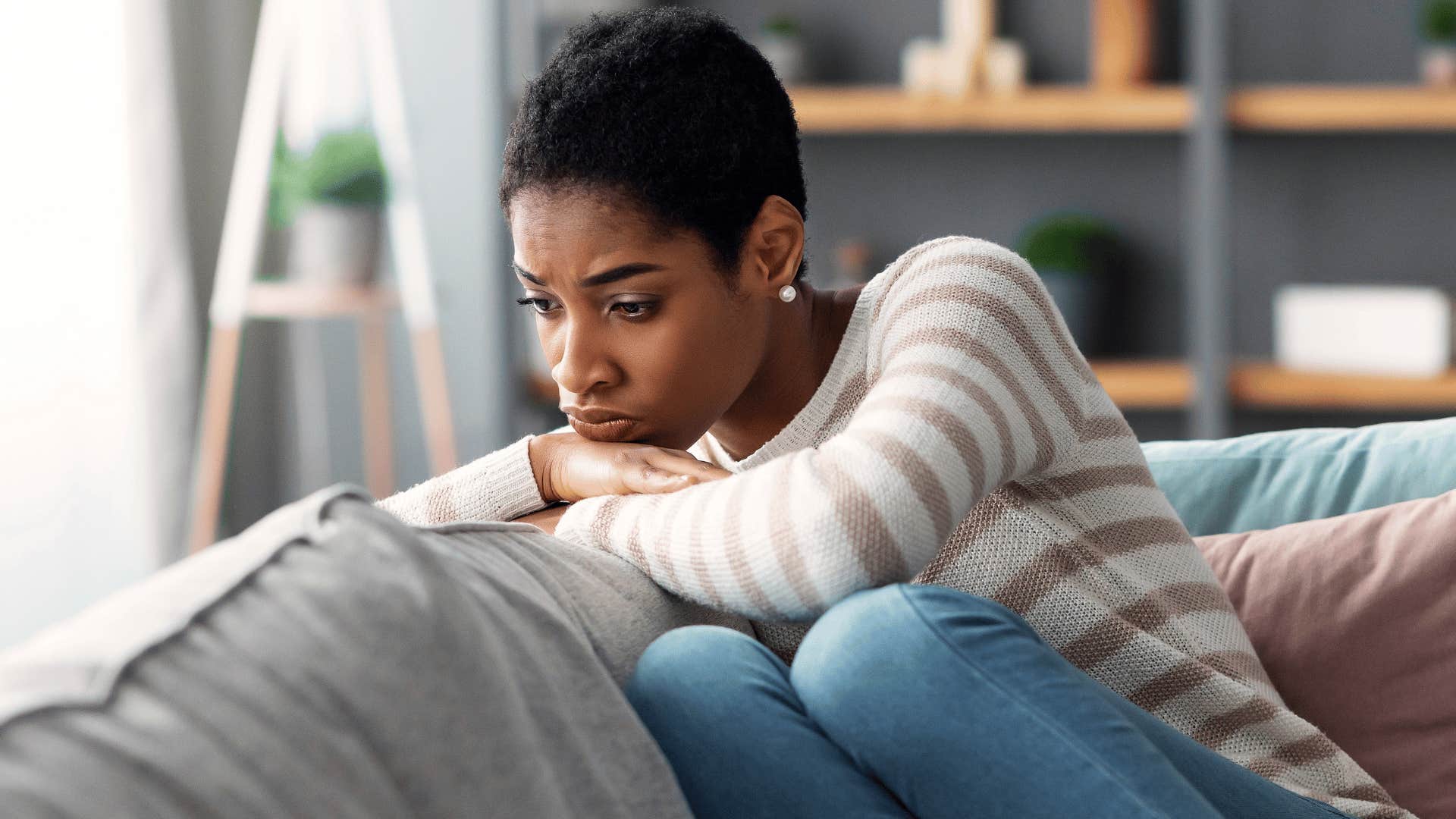 woman in stripped shirt upset on couch as she thinks you'll never understand