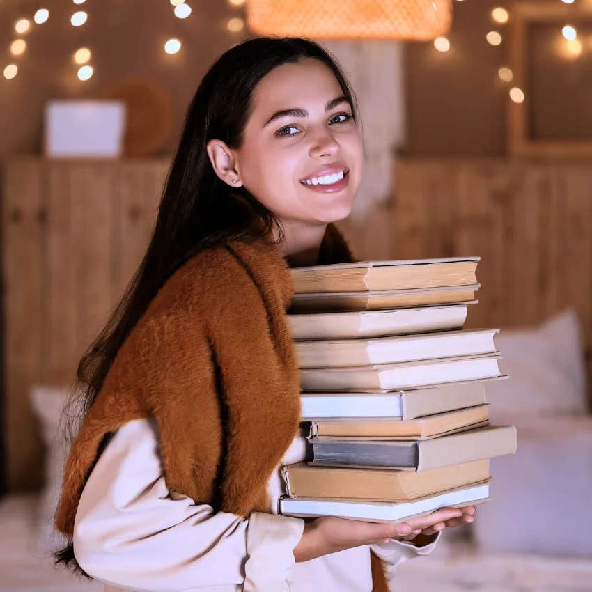 gen z woman holding stack of books inspired by booktok thinking the trend is original