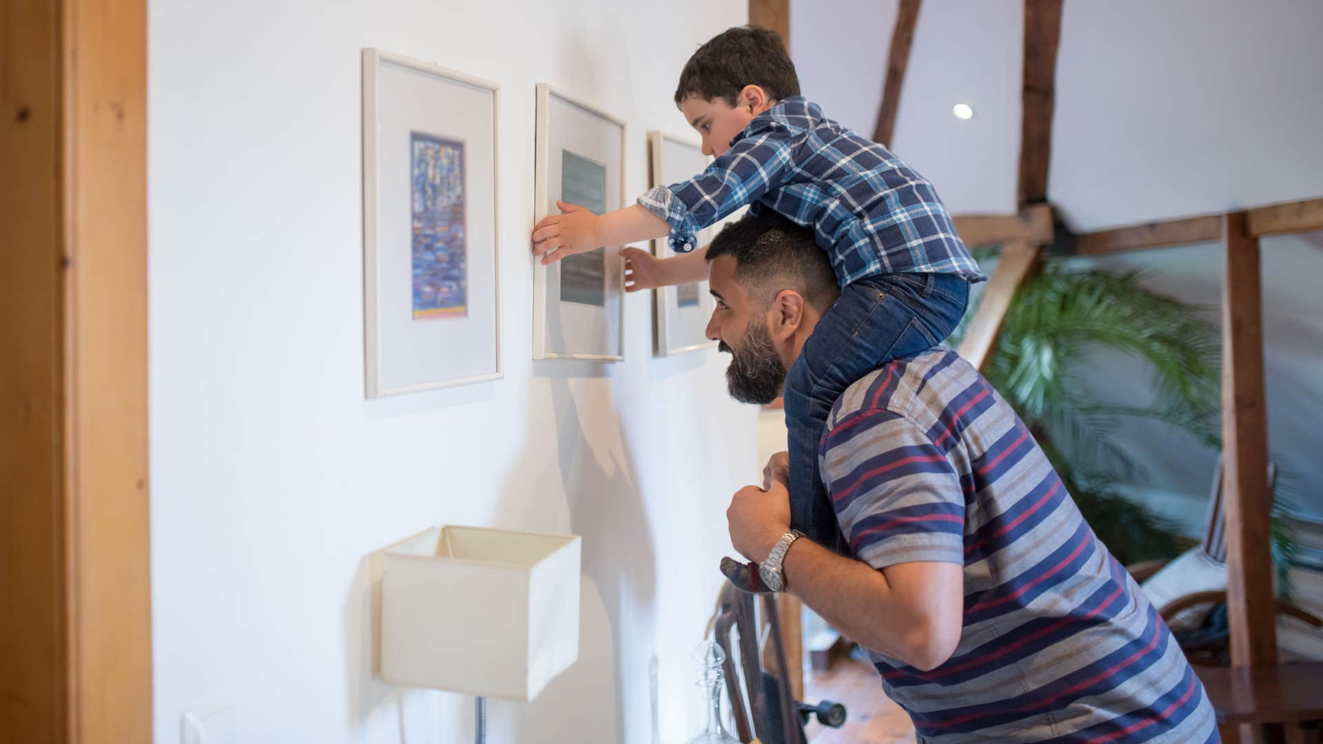 dad helping son hang art at home