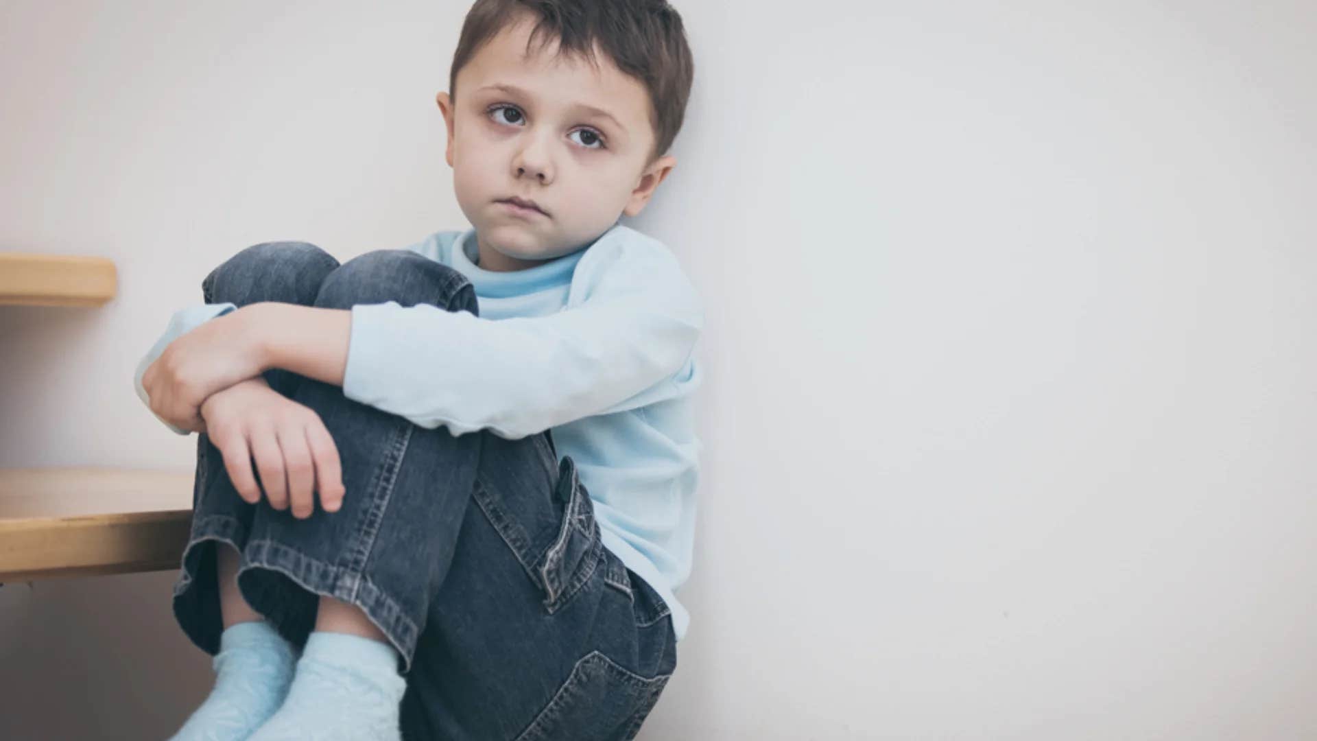 young boy sitting all alone feeling lonely