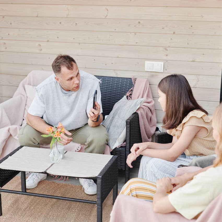 Dad with no boundaries looking through their teenager's phone while the child appears uncomfortable about having their privacy invaded
