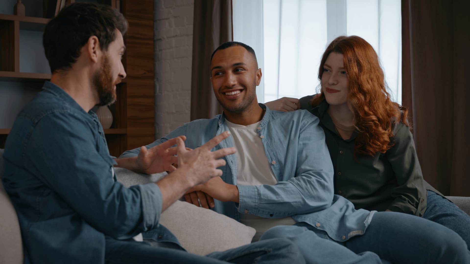 man telling friends i know it's a little cramped in here as they sit on couch