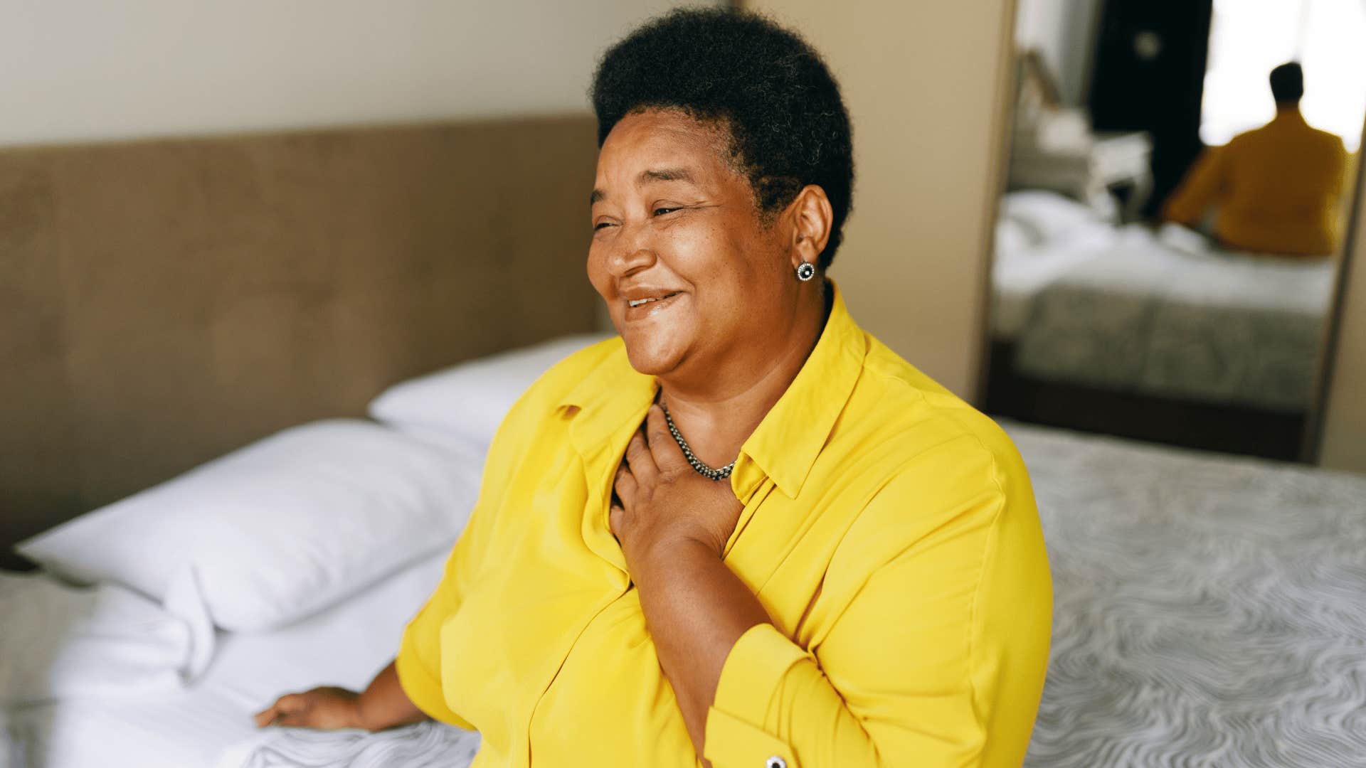 woman in yellow shirt putting hand over heart as they have humility
