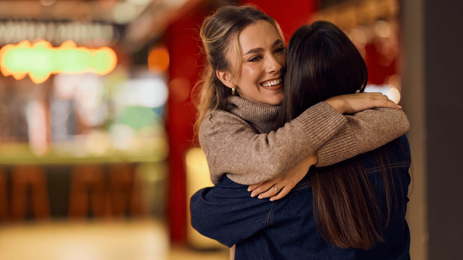 woman in brown sweater hugging friend as they're genuinely kind