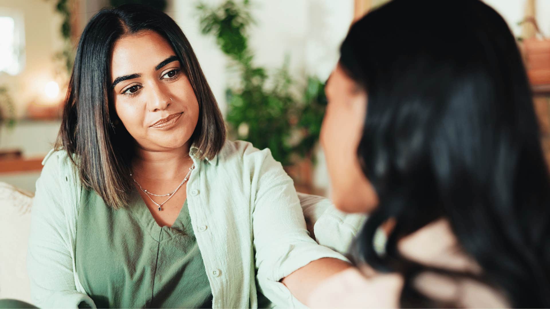 woman in green shirt listening to friend on couch as they're open minded