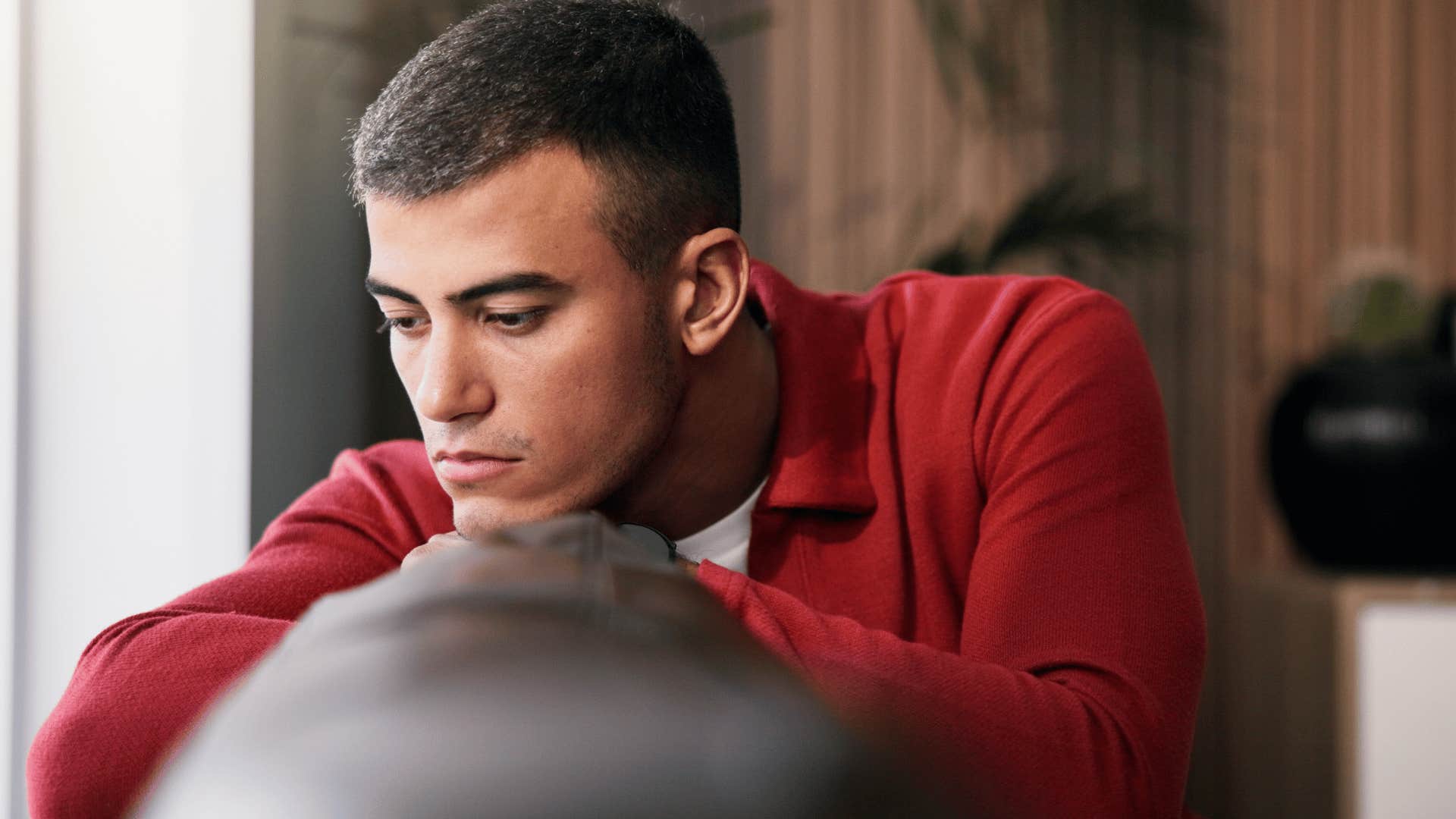 man in red shirt sitting on couch upset as he says i'm not mad i'm just disappointed