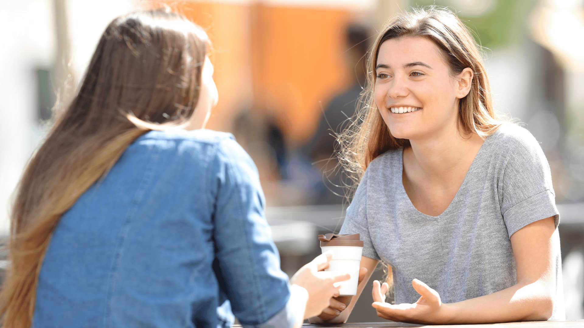 woman in gray shirt at cafe with friend as she tells her they're just jealous