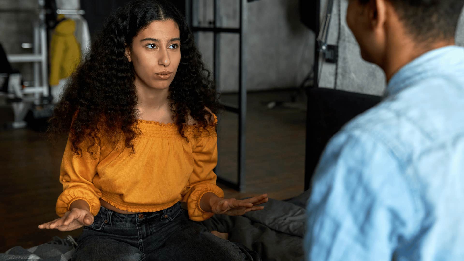woman in orange shirt telling man i'm not going to assume