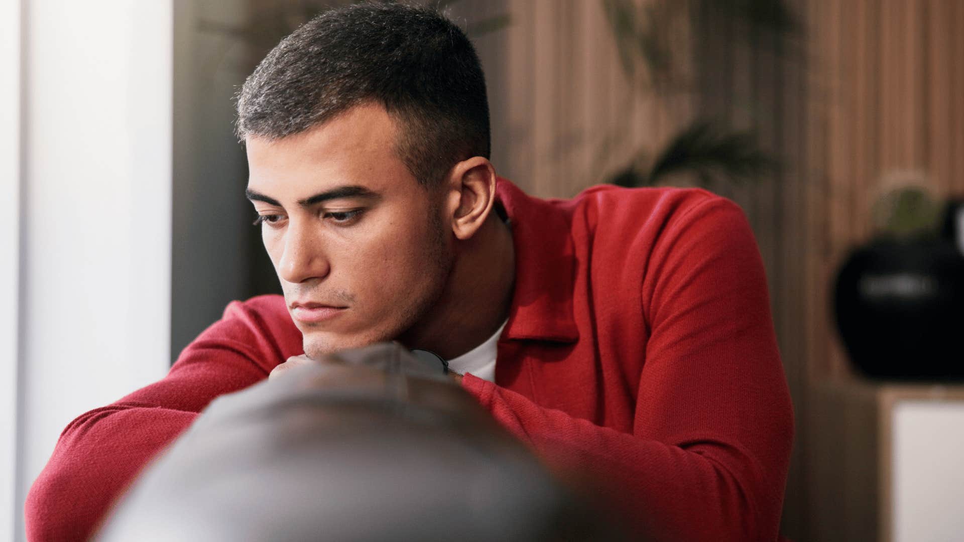 man in red shirt thinking deeply on couch as he thinks all i can do is learn from this