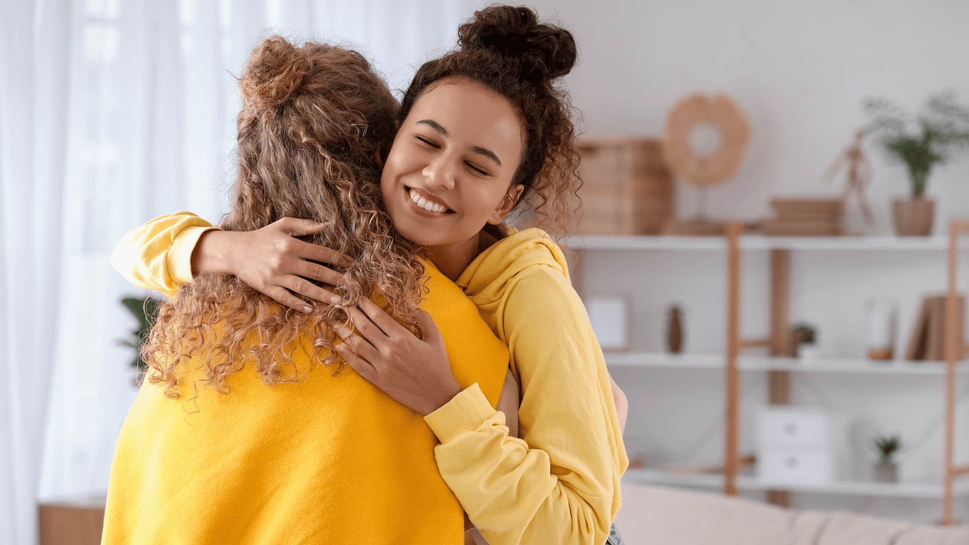 woman in yellow hoodie hugging friend as she says we got this